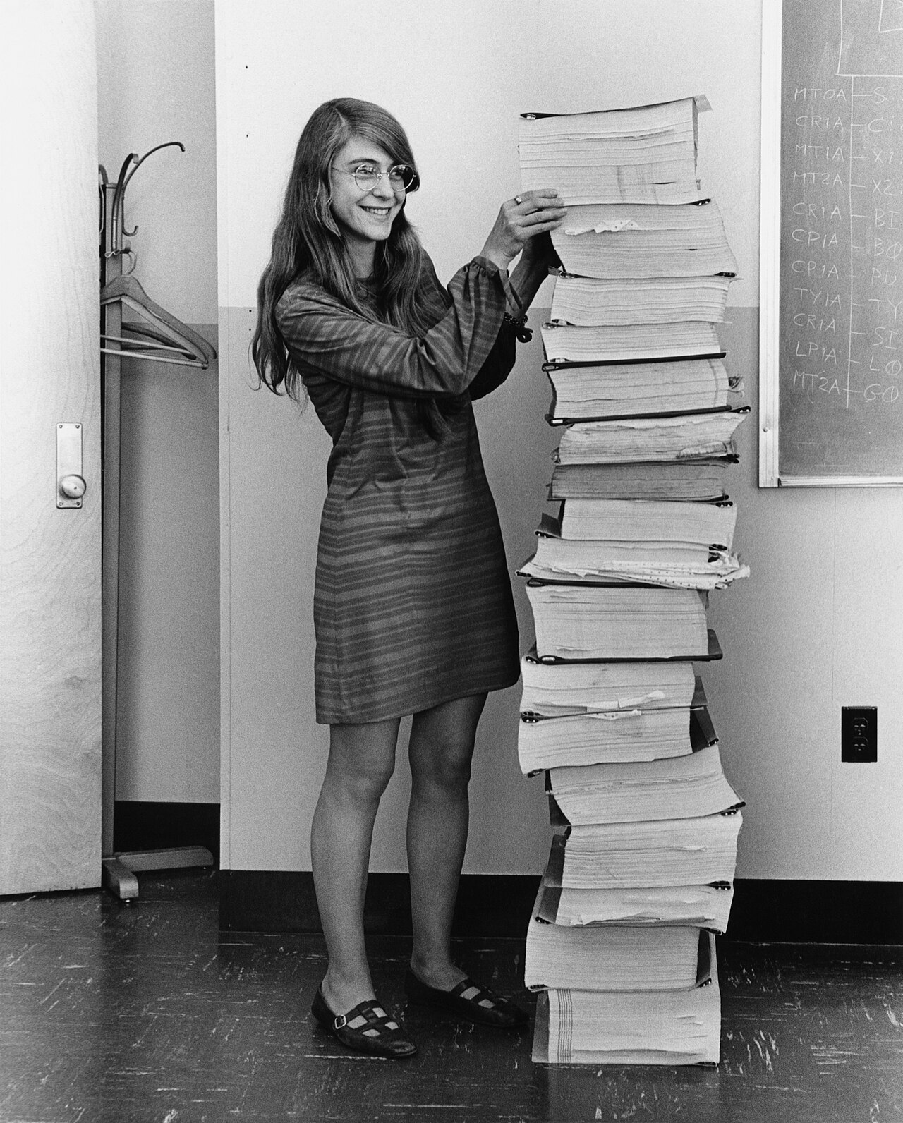 Margaret Hamilton nel 1969, in piedi accanto a una pila di listati stampati del software di bordo di Apollo, alta quanto lei
