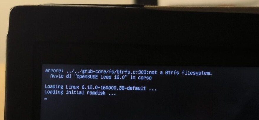 Lo schermo del portatile al primo avvio dopo la migrazione: GRUB stampa "errore: ../../grub-core/fs/btrfs.c:303:not a Btrfs filesystem." e subito dopo carica comunque kernel e initrd di openSUSE Leap 16.0